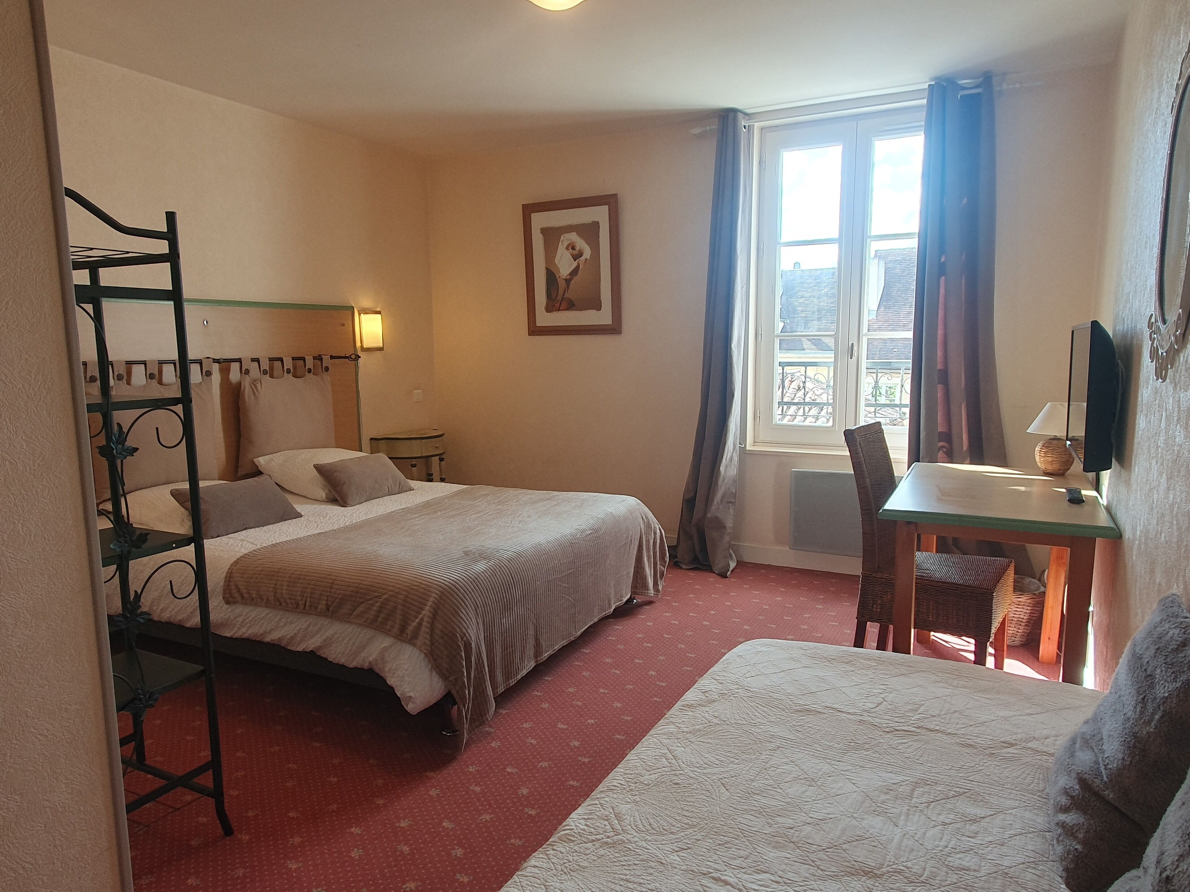 A bedroom with a bunk bed, a desk with a chair, a window with curtains, and a framed picture on the wall.