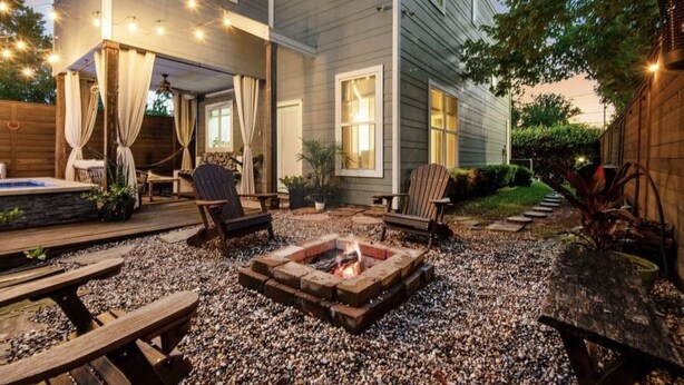Un patio trasero con una fogata, terraza de madera, mobiliario exterior y un jacuzzi.