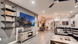Una sala de estar moderna con un televisor de pantalla plana, un sofá de cuero y un comedor con mesa y sillas.