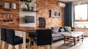 Een moderne woonkamer met een bakstenen muur, een houten eettafel en een bank.