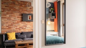 Een moderne woonkamer met een bakstenen muur, een bank, een salontafel en een bed met een blauwe sprei.