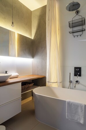 Une salle de bain moderne avec une baignoire sur pieds, un meuble-lavabo en bois, un grand miroir, un porte-serviettes et une pomme de douche.