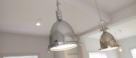 Two pendant lights hanging from the ceiling in a room with white walls and a window.