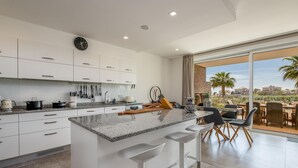 A modern kitchen with white cabinets, a granite countertop, and a bar stool area. - Villa Praia de Branson, with amazing Ocean views (Lagos)
