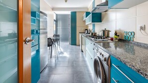 Une cuisine moderne avec des meubles de couleur turquoise, une cuisinière en acier inoxydable et un lave-linge encastré.