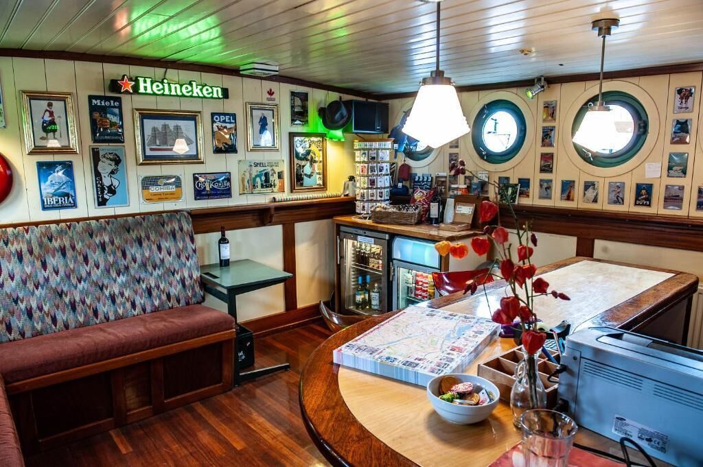 A cozy bar area with a Heineken sign, a wooden bench, a counter with a map, and a vintage radio.