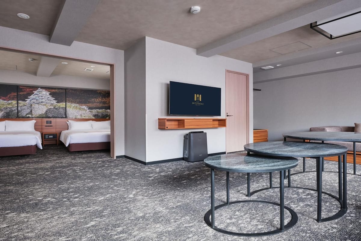 A hotel room with a bed, a desk, a chair, a TV, and a painting.