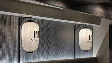 Ein modernes Interieur mit zwei hängenden Laternen mit der Aufschrift 'MONDO' vor einer Wand mit Muster.