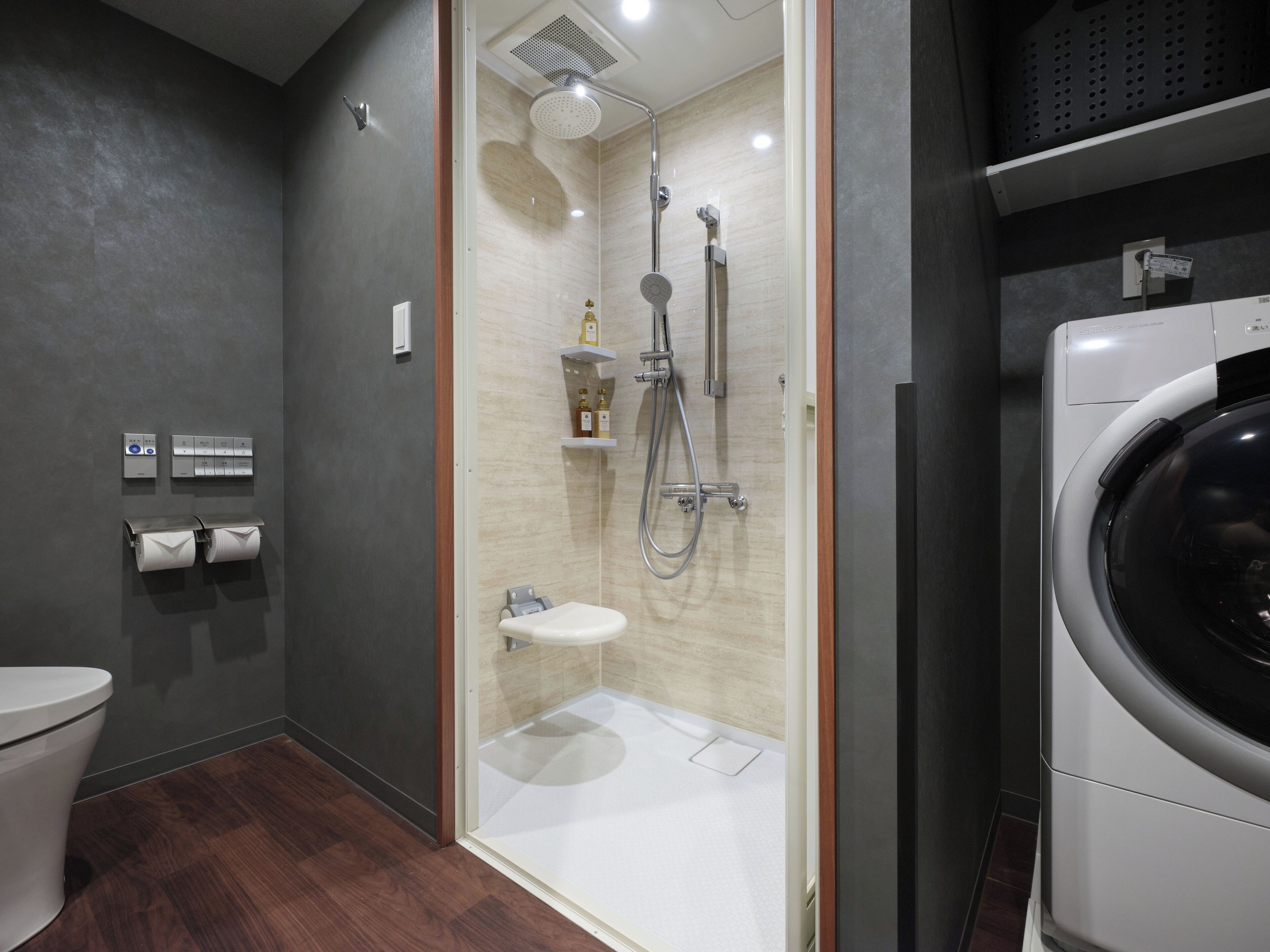 A modern bathroom with a glass-enclosed shower, a toilet, and a washing machine.