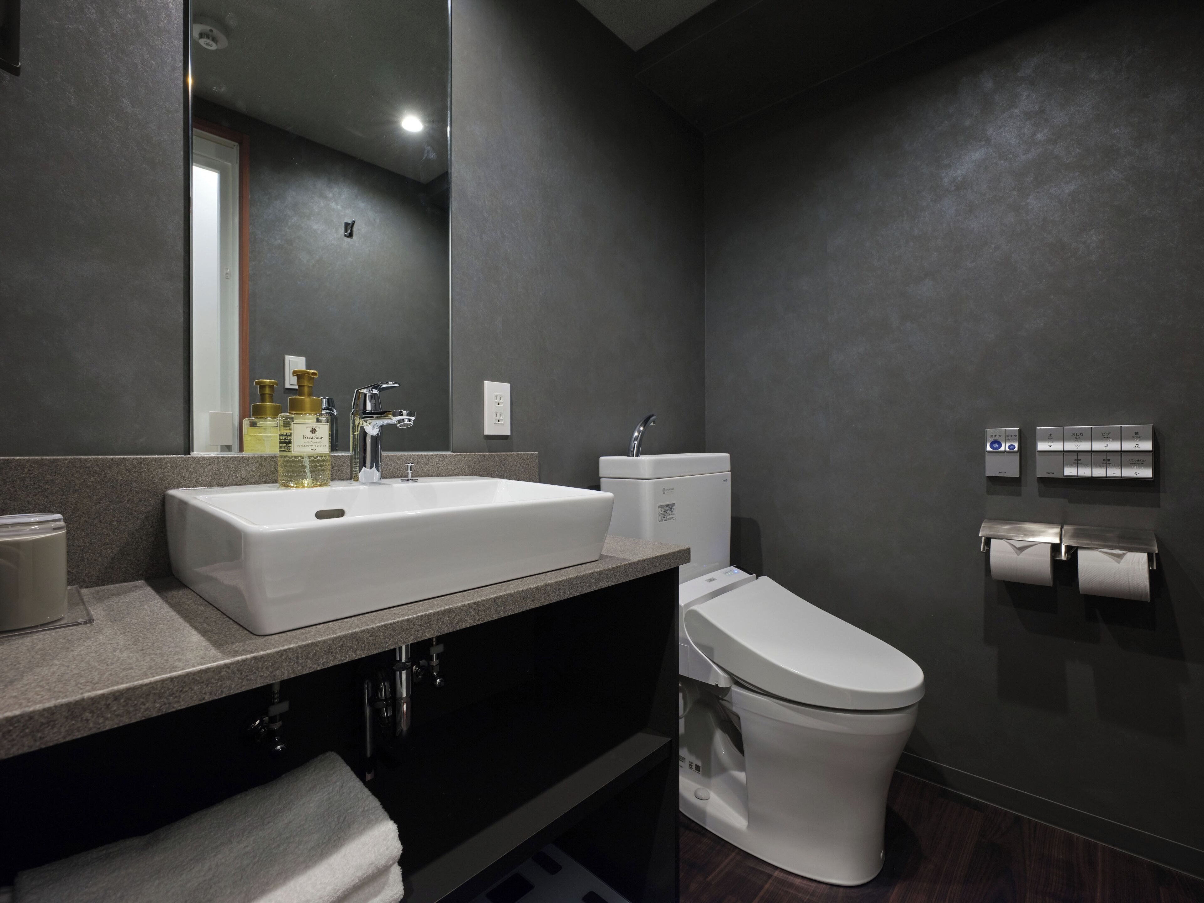 A modern bathroom with a large sink, a toilet, and a mirror.