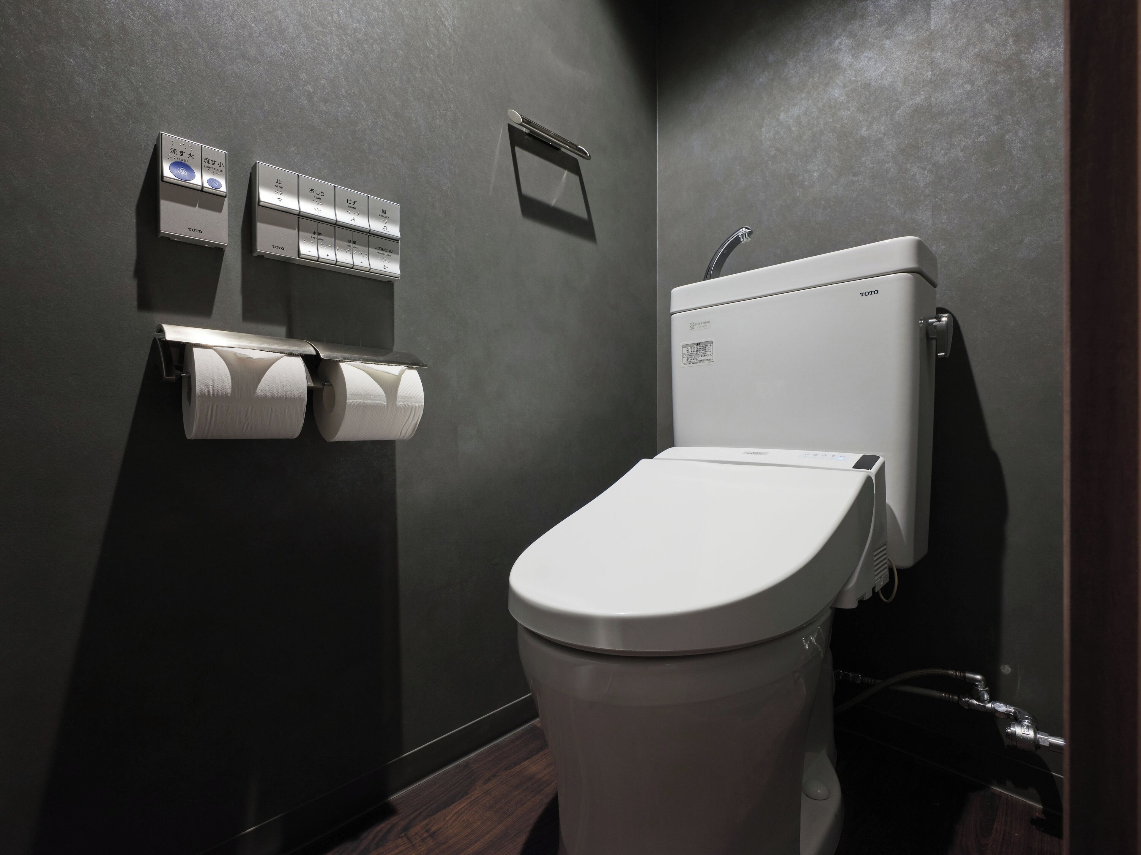 A modern bathroom with a toilet, a paper towel dispenser, and a hand dryer.