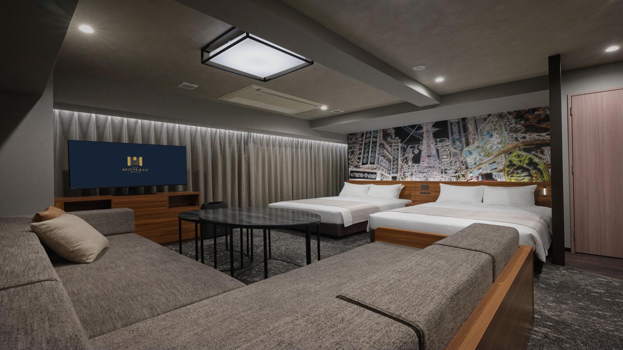 A modern hotel room with a flat-screen TV, a sofa, a bed, and a dining table.