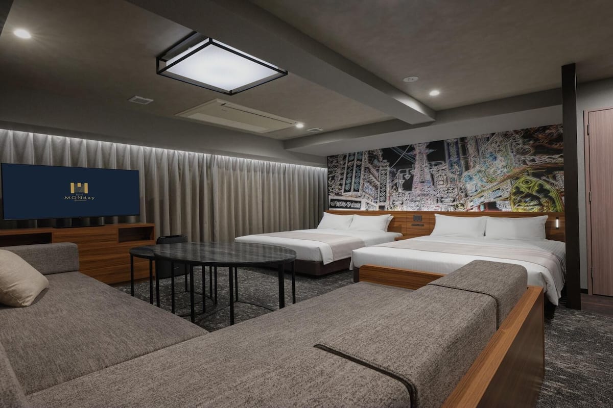 A modern hotel room with a flat-screen TV, a sofa, a bed, and a dining table.
