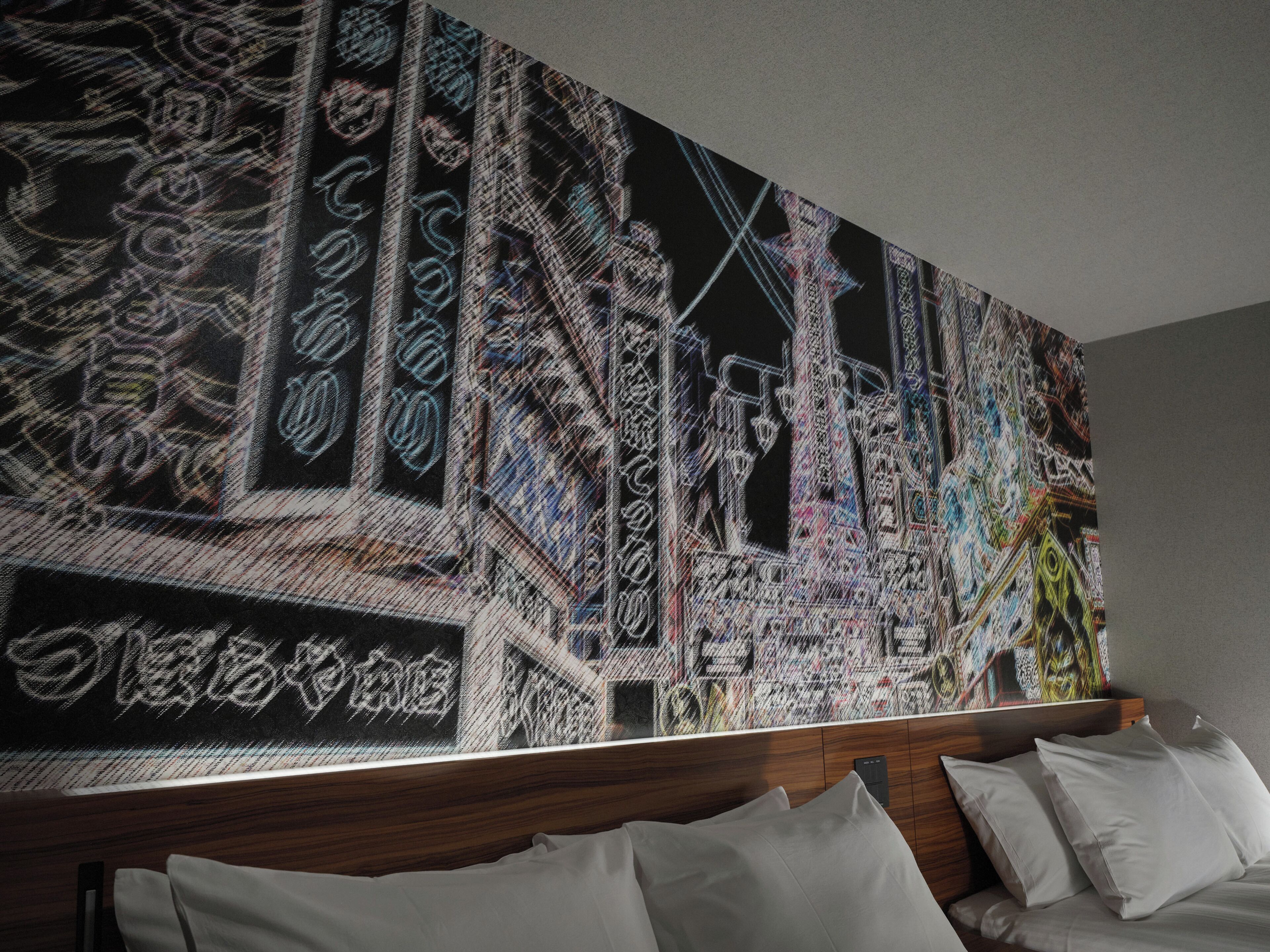 A hotel room with a large abstract painting on the wall, a wooden headboard, and white bedding.