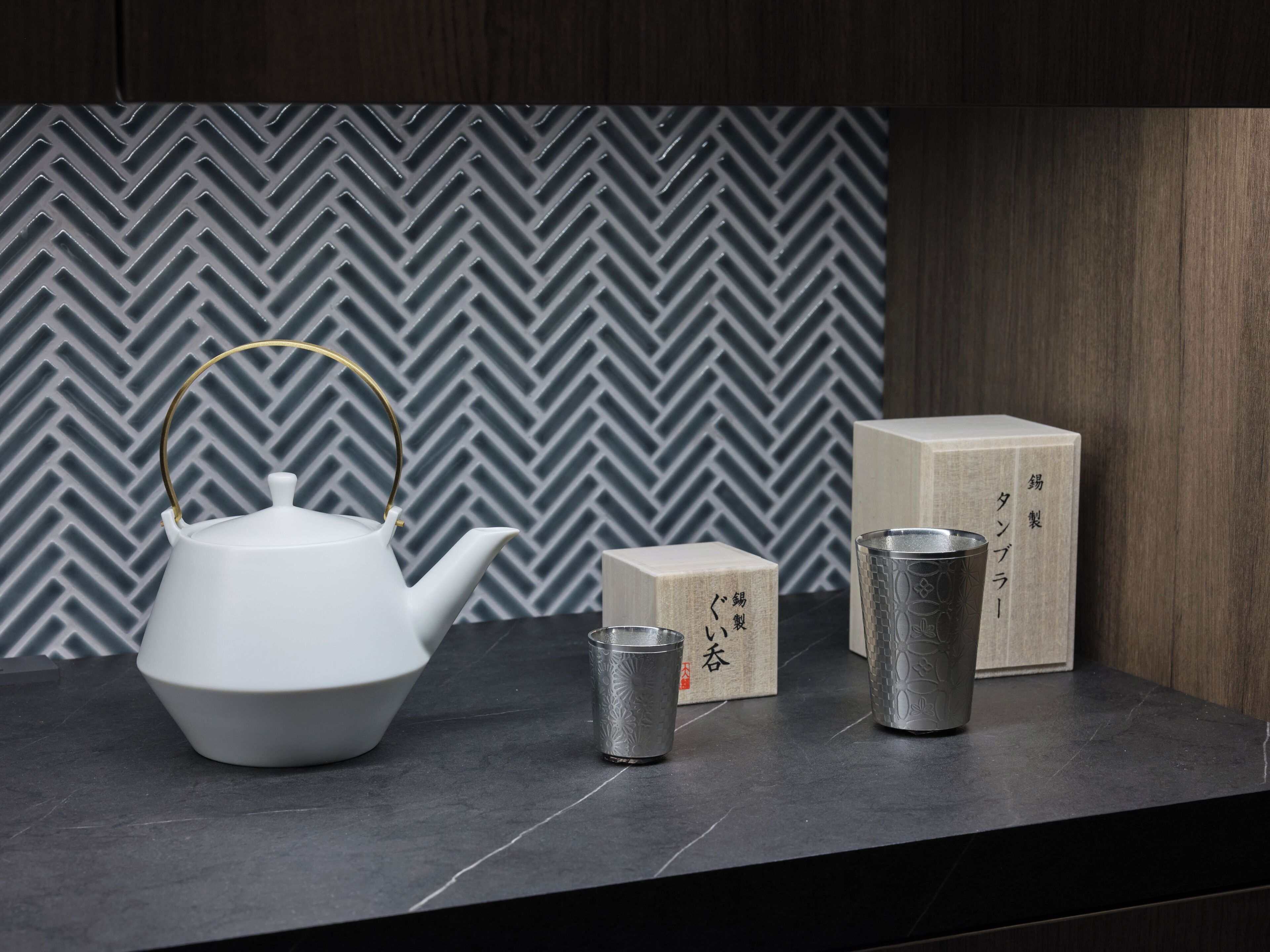 Una encimera de cocina con un hervidor blanco, una taza pequeña y dos cajas.