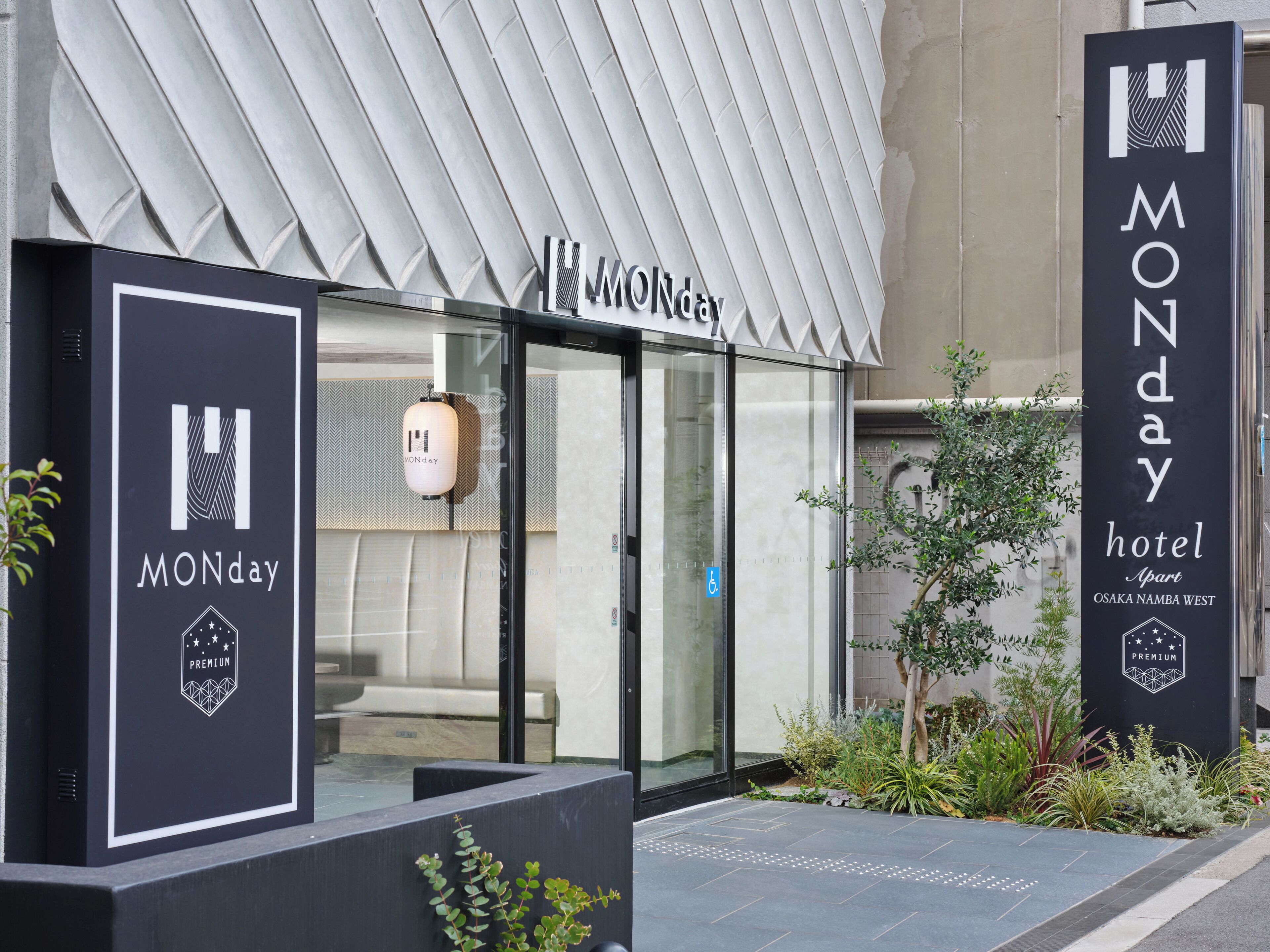 A hotel entrance with a modern design, including a glass door, a sign indicating 'MONday' and 'MONDAY', and a 'PREMIUM' label.