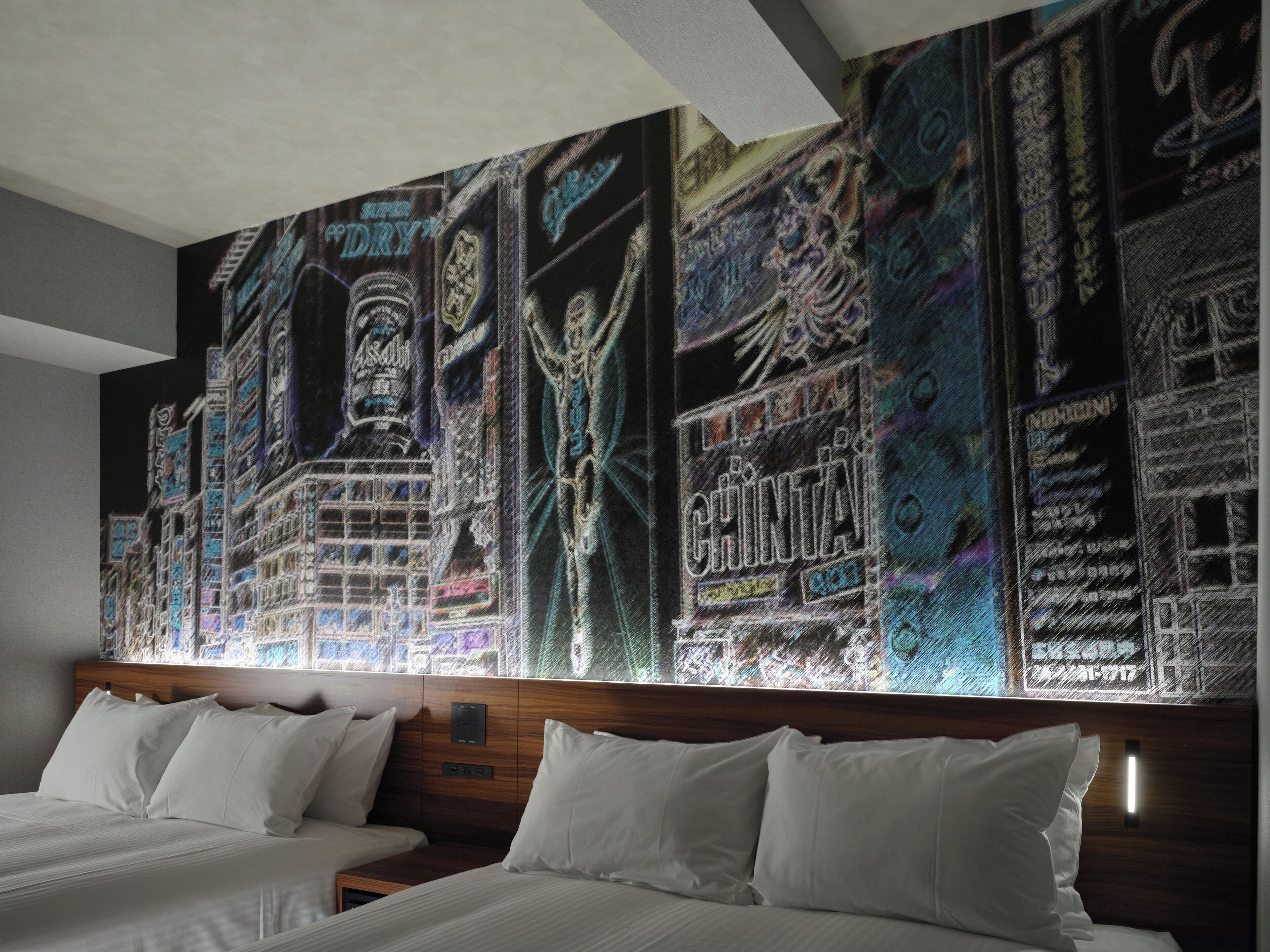 A hotel room with two beds, a large wall mural, and a wooden headboard.
