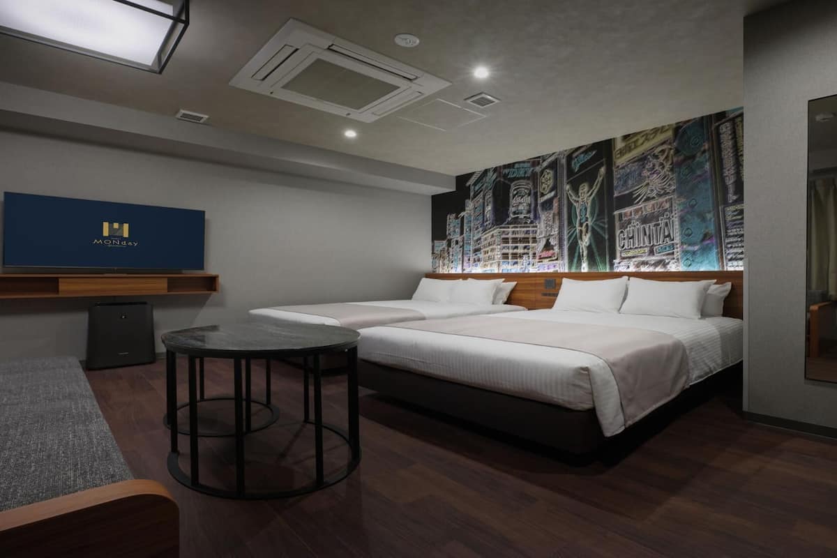 A hotel room with a bed, a small round table, a mirror, a wall-mounted TV, and a ceiling light.
