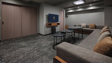 Een moderne, goed verlichte lounge met een flatscreen-tv, comfortabele zitplaatsen en een vloerbedekking.