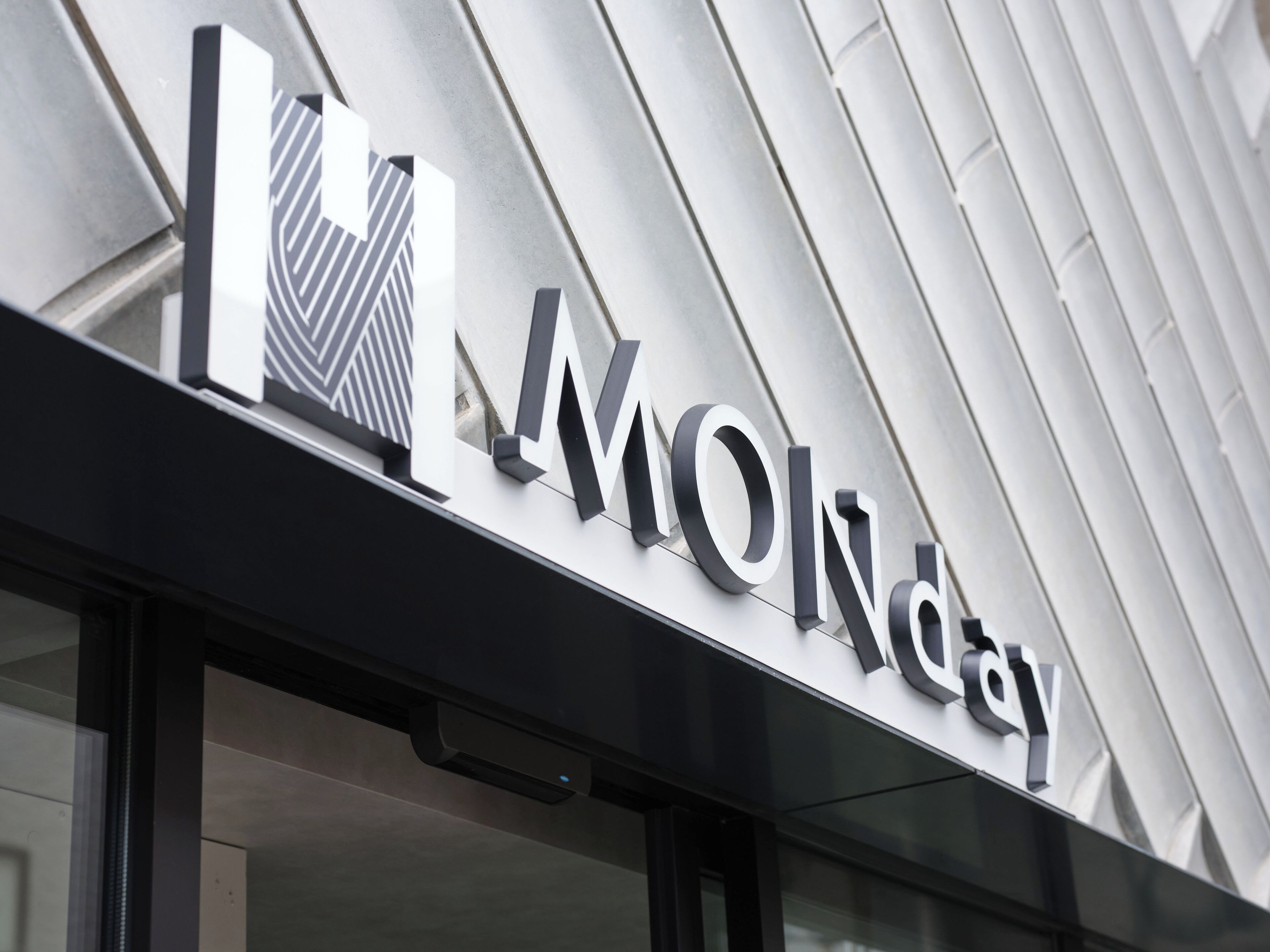 A building with a modern architectural design, featuring a prominent 'MONDAY' sign on the facade.