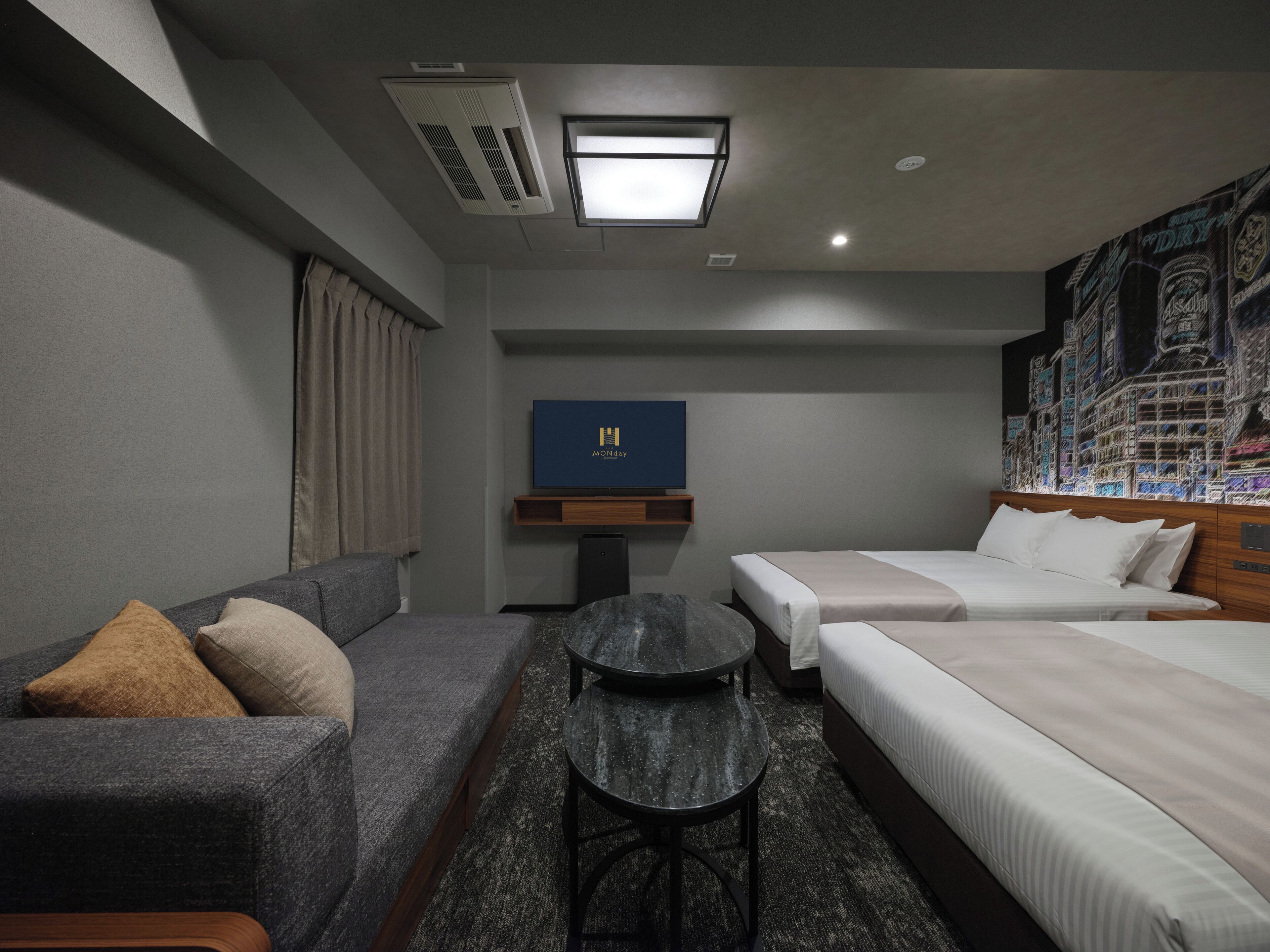 A hotel room with a sofa, a bed, a small table, and a TV.