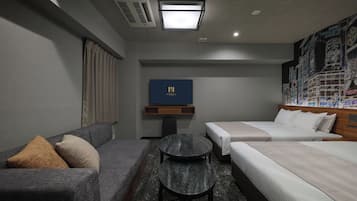 A hotel room with a sofa, a bed, a small table, and a TV.