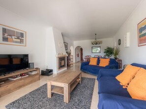 A living room with a TV, fireplace, sofa, and coffee table. - Apt. Alto Golf E2A, with access to a communal pool (Alvor)