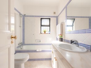 A bathroom with a toilet, sink, bathtub, and a window with plants. - Apt. Alto Golf E2A, with access to a communal pool (Alvor)