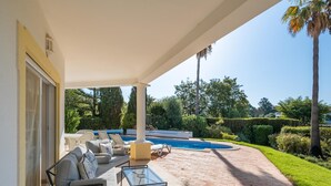 A covered outdoor area with a pool, a sofa, and a glass table. - Casa Oliveiras, villa with private pool & garden (Alvor)