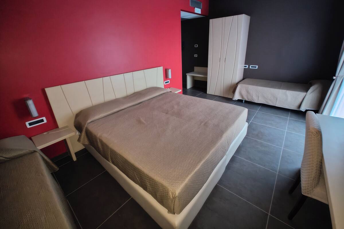 Moderni hotellihuone, jossa on suuri sänky, yöpöytä, tuoli, vaatekaappi ja pieni pöytä.
