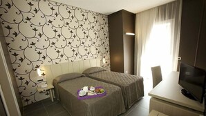 A hotel room with two beds, a desk with a TV, and a breakfast tray on the beds. - Sunrise Hotel (Casoria)