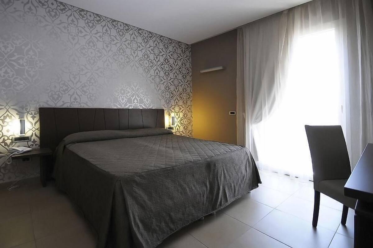 Moderni hotellihuone, jossa on suuri sänky, työpöytä ja tuoli.