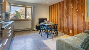 A modern kitchen with a large window, a dining area with a table set for two, and a cozy seating area with a sofa. - Charming 2-room in Val d'Isère - WIFI, for 4 pers (Val-d'Isère)