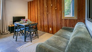 A dining area with a wooden wall, a window with a view, and a sofa. - Charming 2-room in Val d'Isère - WIFI, for 4 pers (Val-d'Isère)