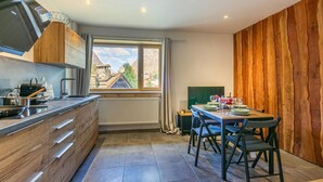 A modern kitchen with a dining area, wooden paneling, and a view of a mountainous landscape. - Charming 2-room in Val d'Isère - WIFI, for 4 pers (Val-d'Isère)