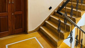 A staircase with ornate metal railings leading to an upper floor, a wooden door, and a framed artwork on the wall. - Hotel Diamond Villa Safari Jaisalmer  (Jaisalmer)