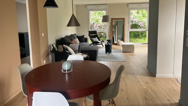 Un salon moderne avec un coin repas, de grandes fenêtres et une vue sur la verdure.
