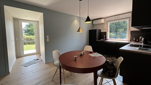 Une cuisine moderne avec une table de salle à manger ronde, des chaises blanches et des luminaires suspendus.