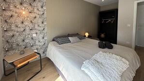 Une chambre à coucher avec un lit, une table de chevet, une lampe et une armoire.