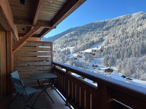 Un balcon en bois offrant une vue sur un paysage montagneux enneigé.