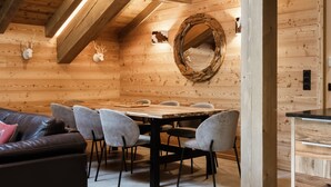 A wooden interior with a dining table, chairs, a sofa, and a mirror.