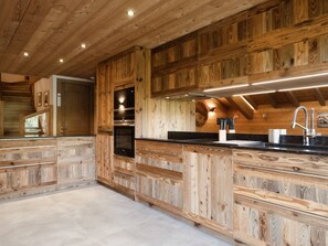 Une cuisine avec un lambris en bois, un plan de travail noir, des appareils en acier inoxydable et un robinet moderne.