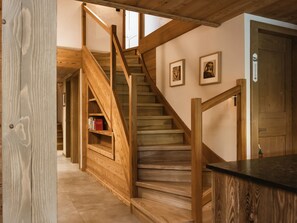 A wooden staircase with a wooden railing, a bookshelf, and framed pictures on the wall.