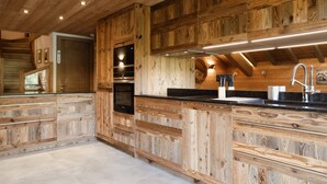 A kitchen with wooden paneling, a black countertop, stainless steel appliances, and a modern faucet.