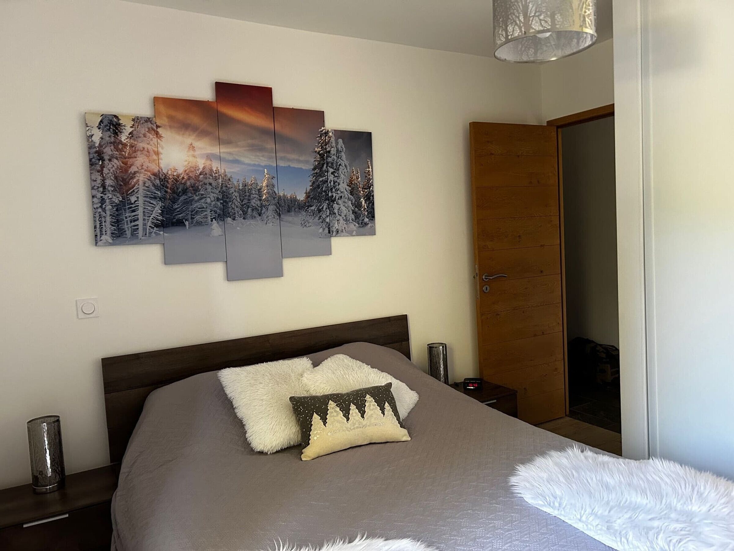 A bedroom with a bed, a nightstand, a lamp, and a door.