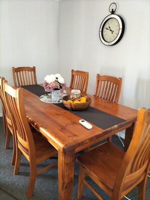 Enjoy meals in this cozy dining area with a table for six, a vase with fresh flowers, and a bowl of seasonal fruit.