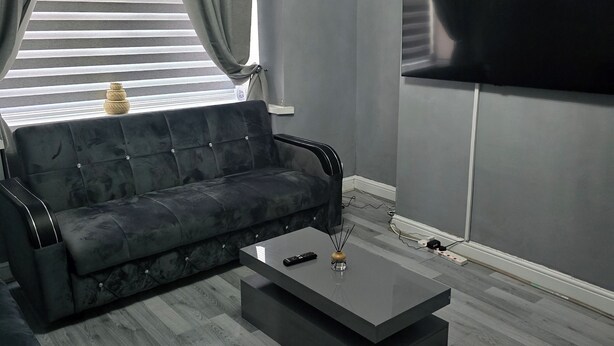 Un salon moderne avec un canapé gris, une table basse et un téléviseur à écran plat fixé au mur.