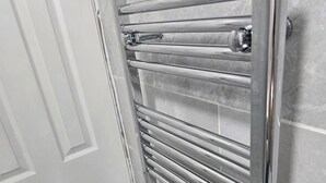 Une salle de bain avec un porte-serviettes chromé, une porte blanche et des murs recouverts de carreaux gris.