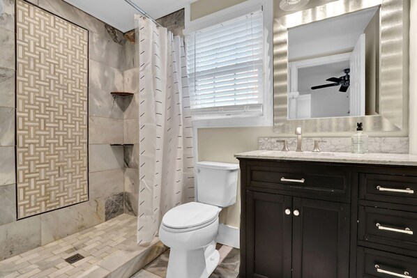 A bathroom with a shower, toilet, and dark cabinetry. - Heart of Buckhead Message Now for Summer Special (Atlanta)