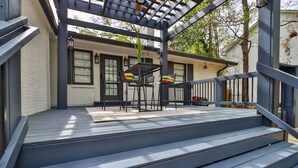 A covered outdoor area with a wooden deck, a pergola, and a seating area with chairs and a table. - Heart of Buckhead Message Now for Summer Special (Atlanta)